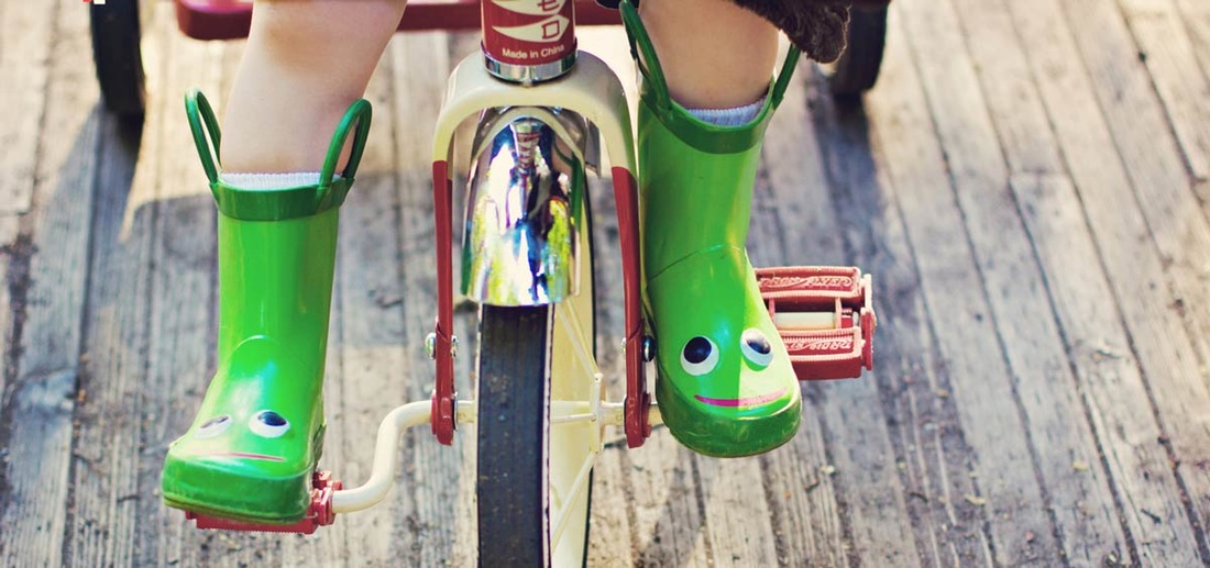 Child on tricycle with green boots